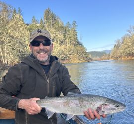 fisherman with a steelhead riverside
